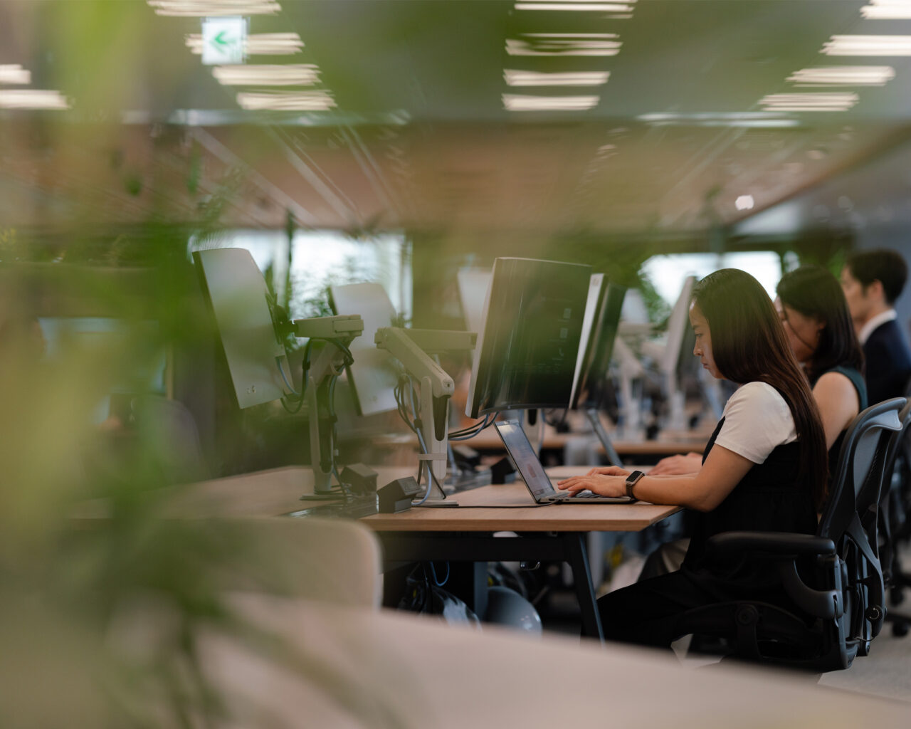 people doing work on their computers at a communal desk